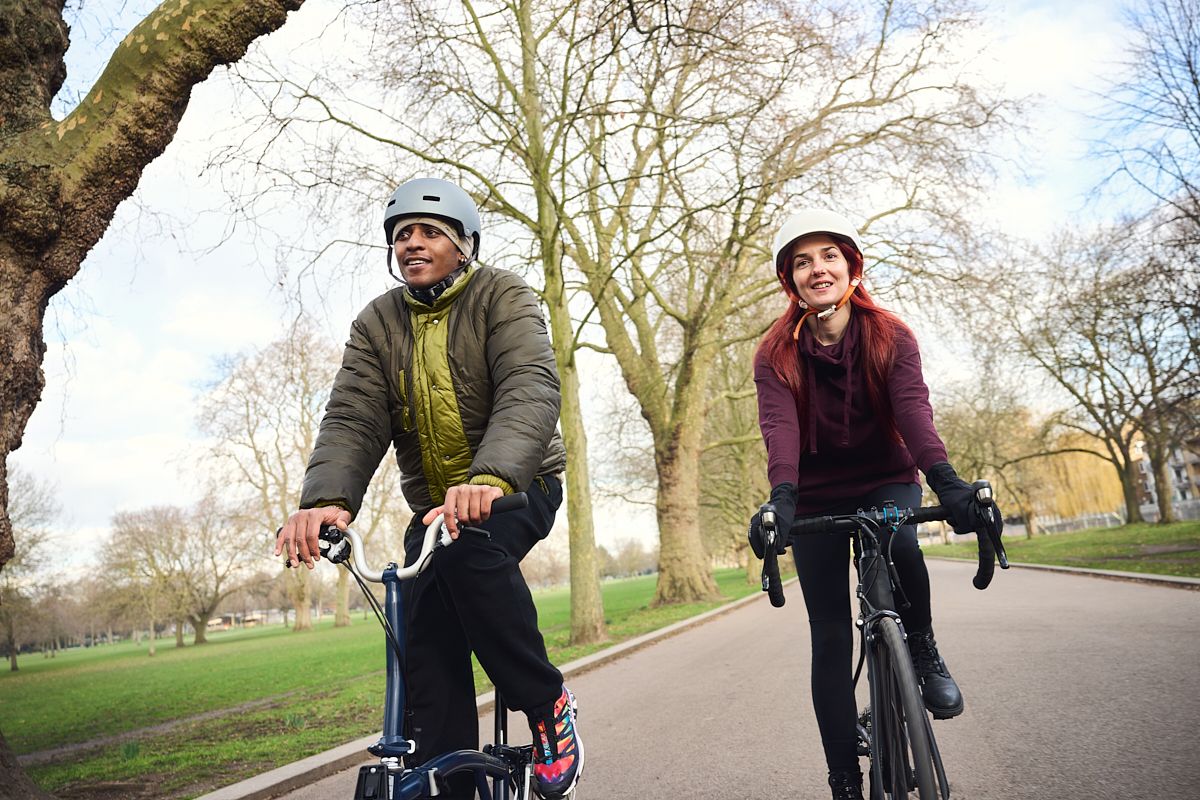 Two people cycling outdoors through a park